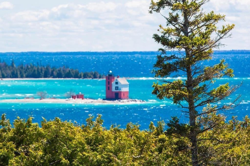 Round Island Lighthouse stands in the deep blue waters off Mackinac Island as viewed from high above the shore