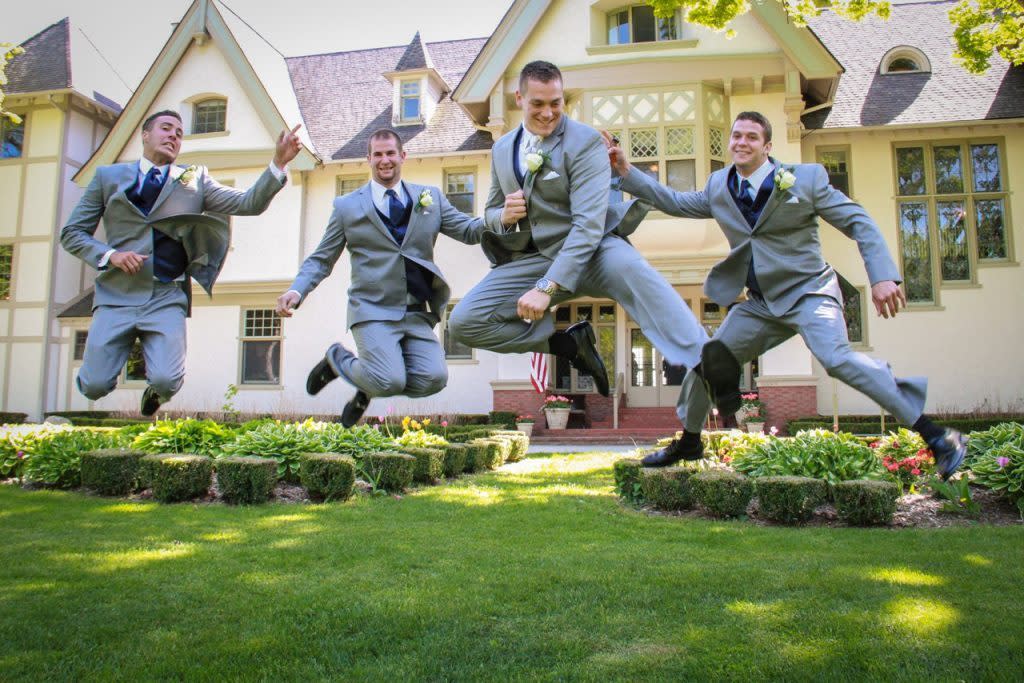 Three wedding groomsmen leap off the ground outside the Inn at Stonecliffe on Michigan's Mackinac Island