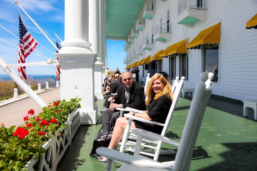 Business meeting attendees sit on rocking chairs on the front porch of Mackinac Island’s Grand Hotel on a sunny day