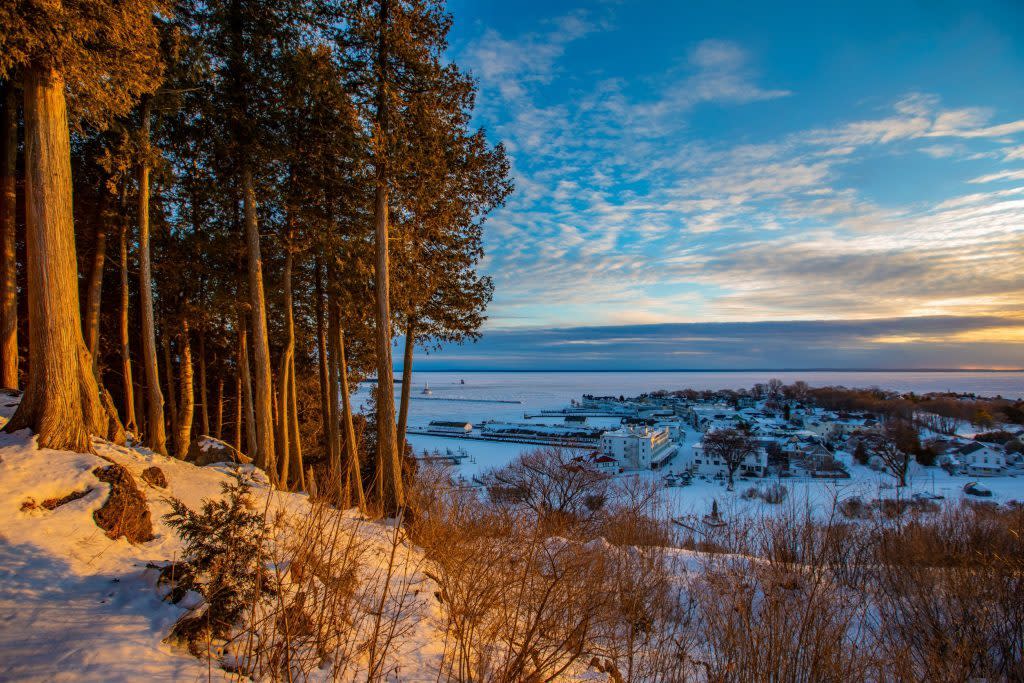 The sun sets on a snow-covered Mackinac Island bluff high above downtown shops and restaurants