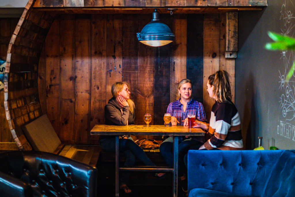 Three people sitting in a booth at Draft & Vessel in Wauwatosa