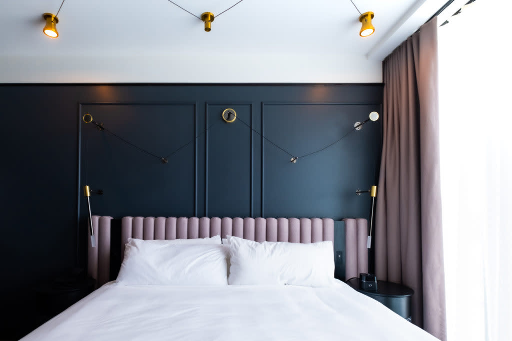 Bed made up with white sheets and mauve bedboard with black wall background at Renaissance Milwaukee West