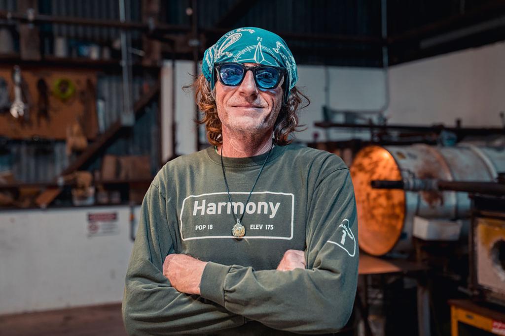 Man standing in front of glass furnace in Harmony t-shirt