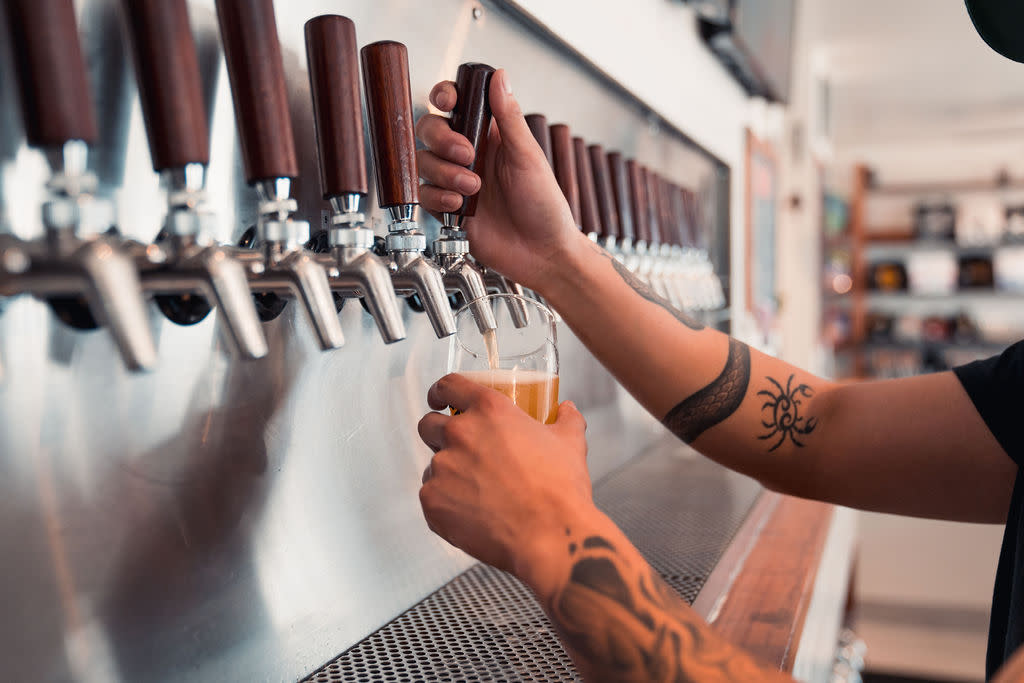 Server pouring beer from wall of taps