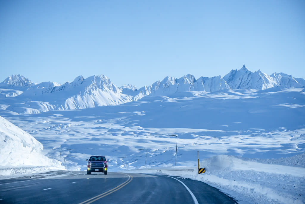 a truck driving on a highway in a mountain pass in winter