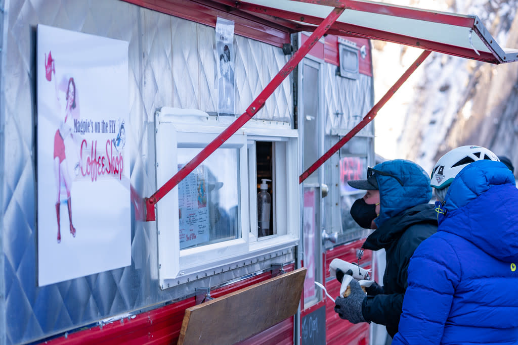 ice climbers in winter gear order coffee at a food truck in a frozen canyon