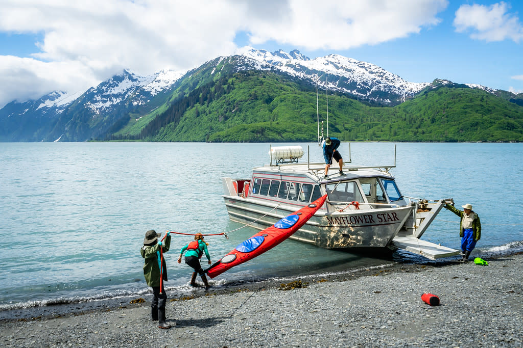 kayaks being unloaded from a water-taxi in a remote bay