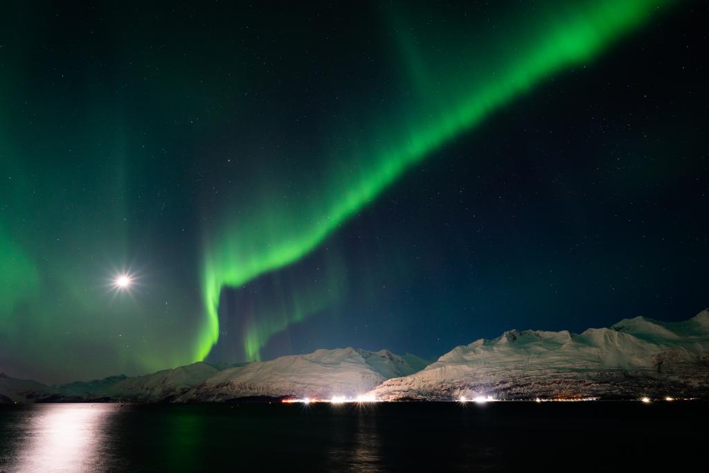 Aurora over a seaside town, port, and mountains