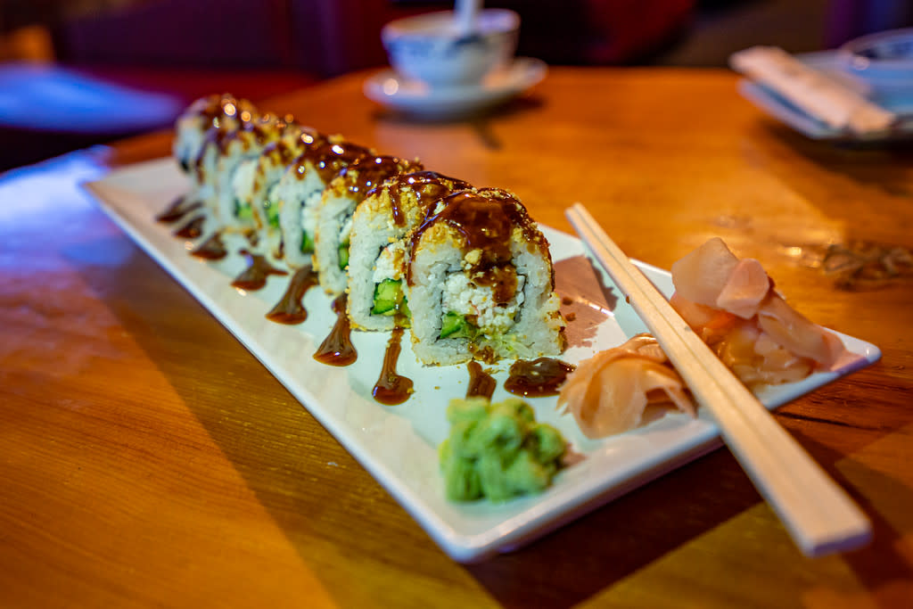 a sushi roll and chopsticks on a plate on a table