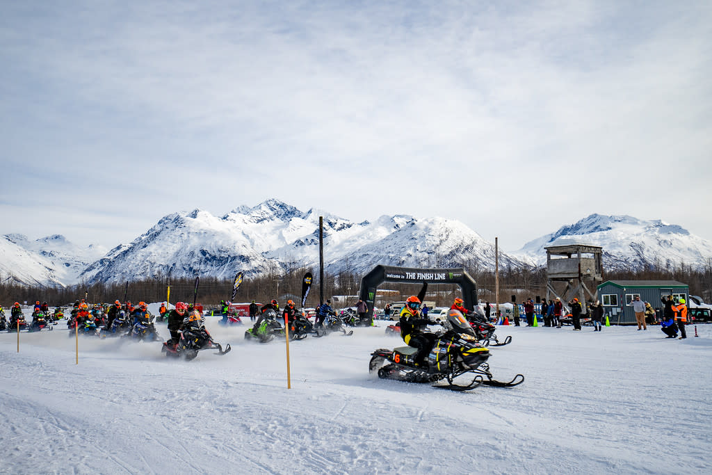 snowmachine racers take off from a start line