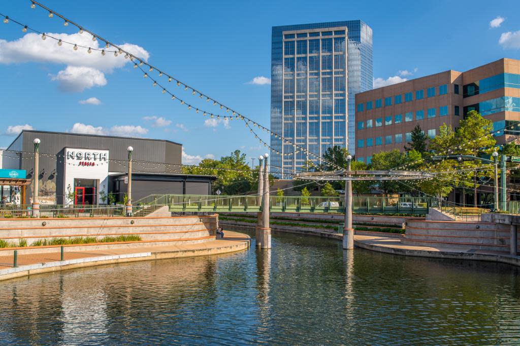 Exterior of North Italia restaurant facing The Woodlands Waterway with a green pedestrian bridge over the water
