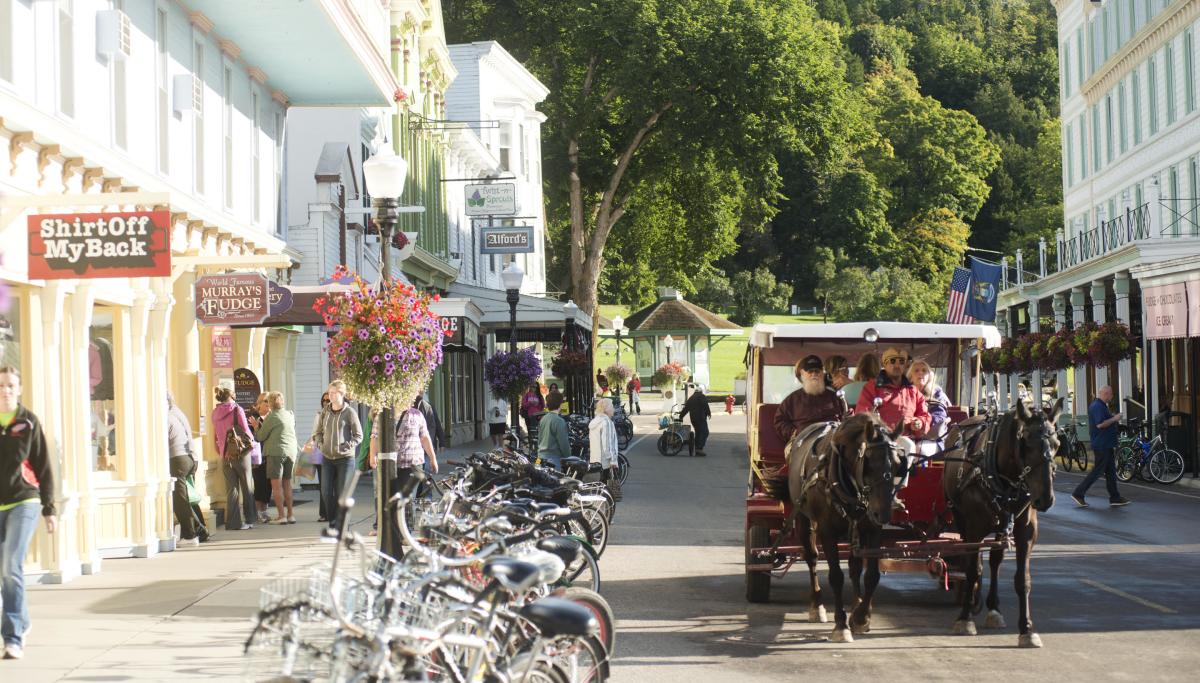 Horse-drawn taxi on a road lined with parked bicycles on Mackinac Island