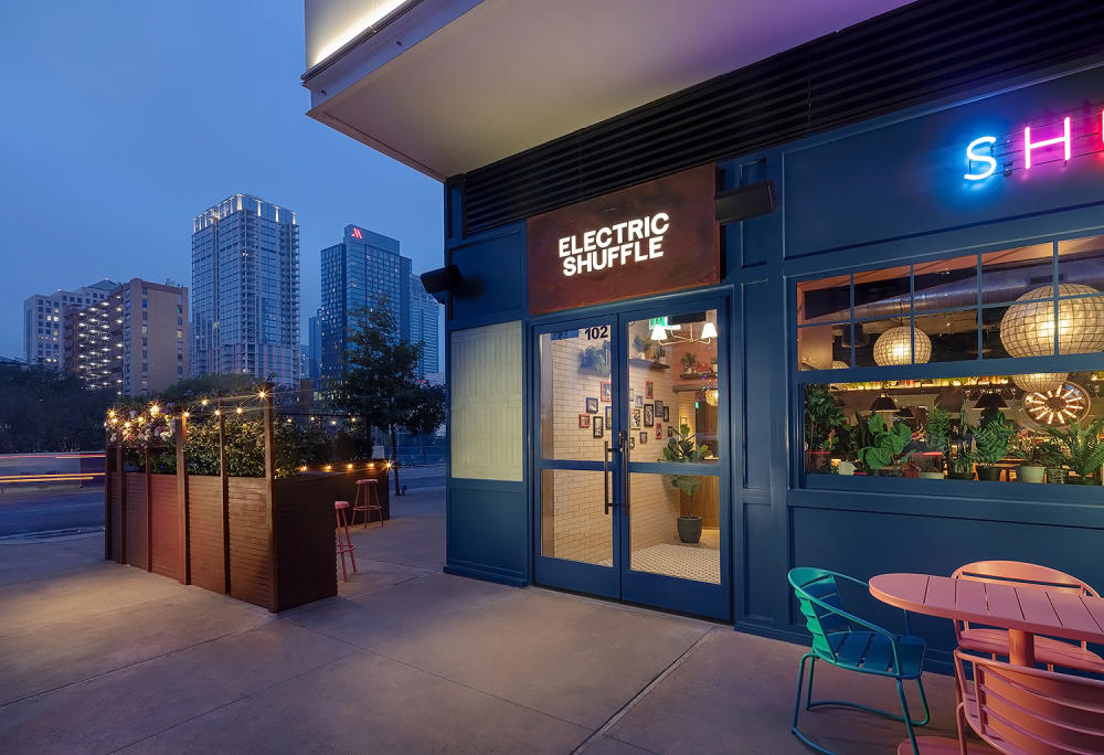 Exterior of Electric Shuffle with downtown skyline in the background.