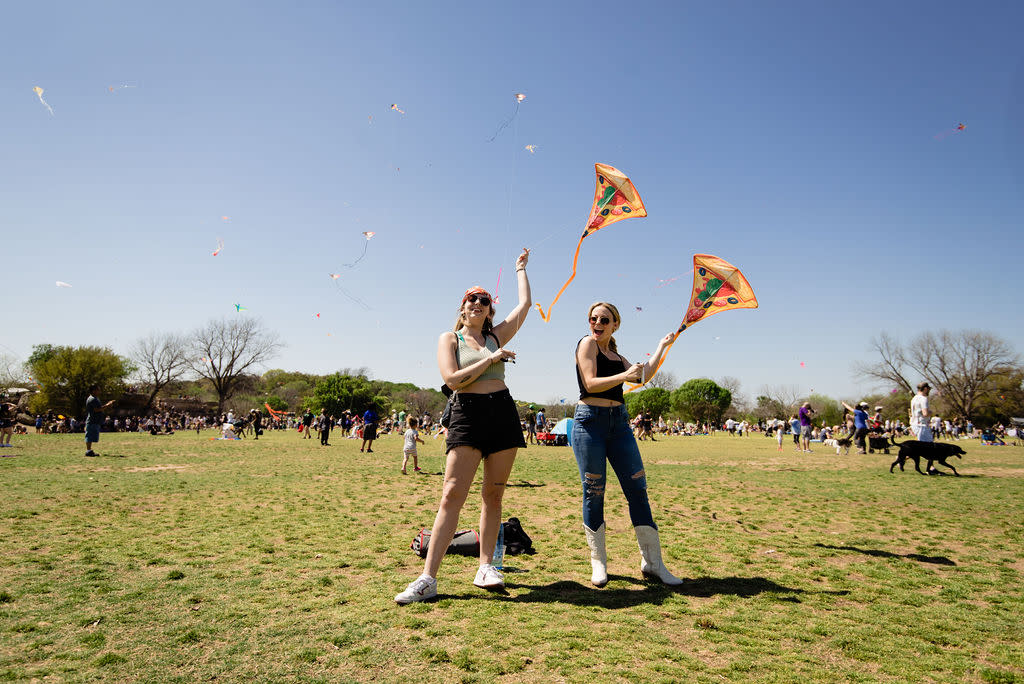 Two women holding identical kites up in the sky at the ABC Kite Festival.