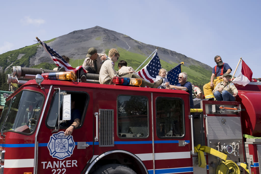 Parade participants sit a top a firetruck in front of Mount Marathon, Seward, Alaska