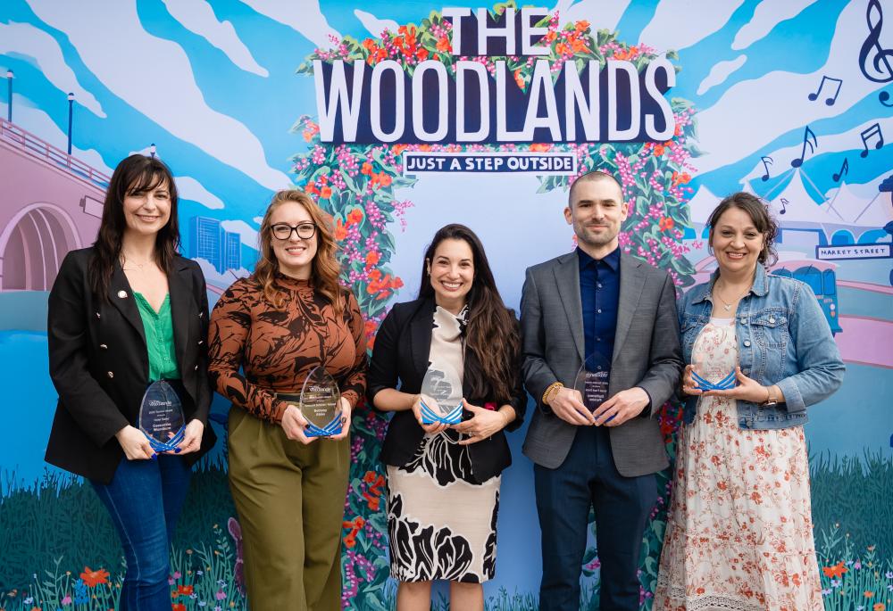 For National Travel and Tourism Week, the winners of Visit The Woodlands' hospitality awards stand in front of a colorful mural of The Woodlands. From left: Cassondra Woodburn, Bethany Ables, Ilyssa Burkowitz, Guillermo Pereira, and Katrina Lockler.