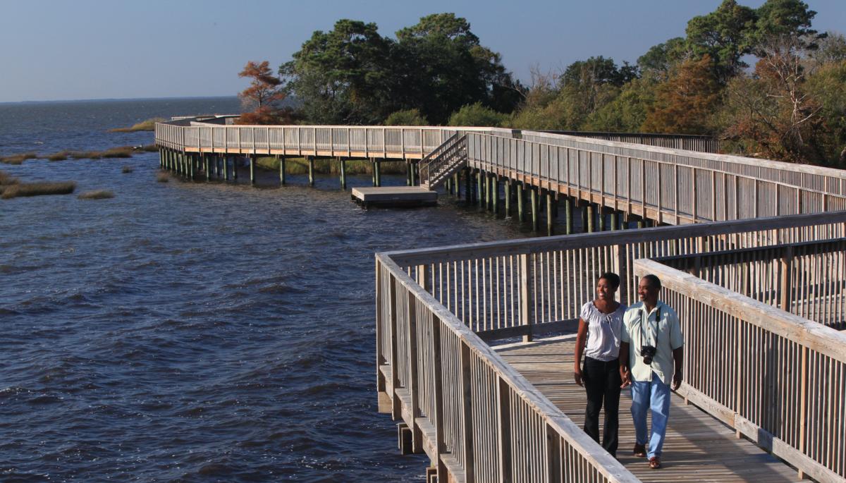 A couple walks along the Duck Boardwalk looking out over the sound waters.