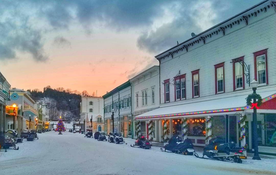 Snow-covered Main Street on Mackinac Island lined with snowmobiles and decorated for the holidays