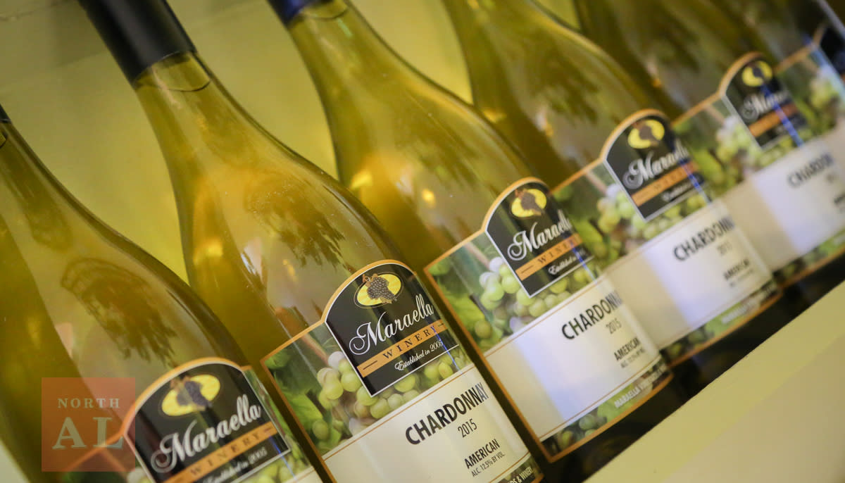 A row of white wine bottles labeled "Maraella Winery Chardonnay 2015"