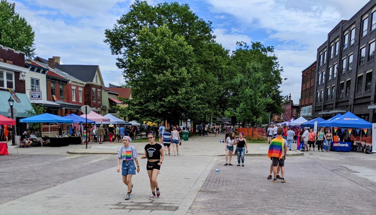 Booths and people and trees under a sunny sky for NKY Pride Festival in Mainstrasse Village Covington, KY