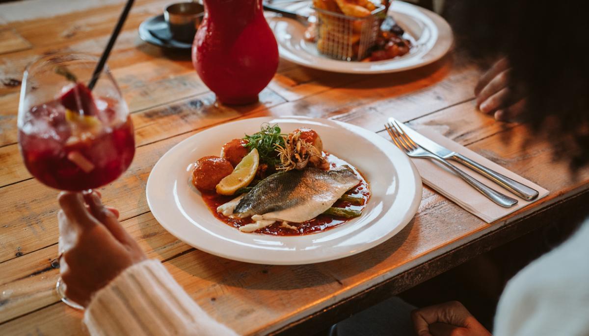 Woman sitting at a table with a plate of seafood and a cocktail.