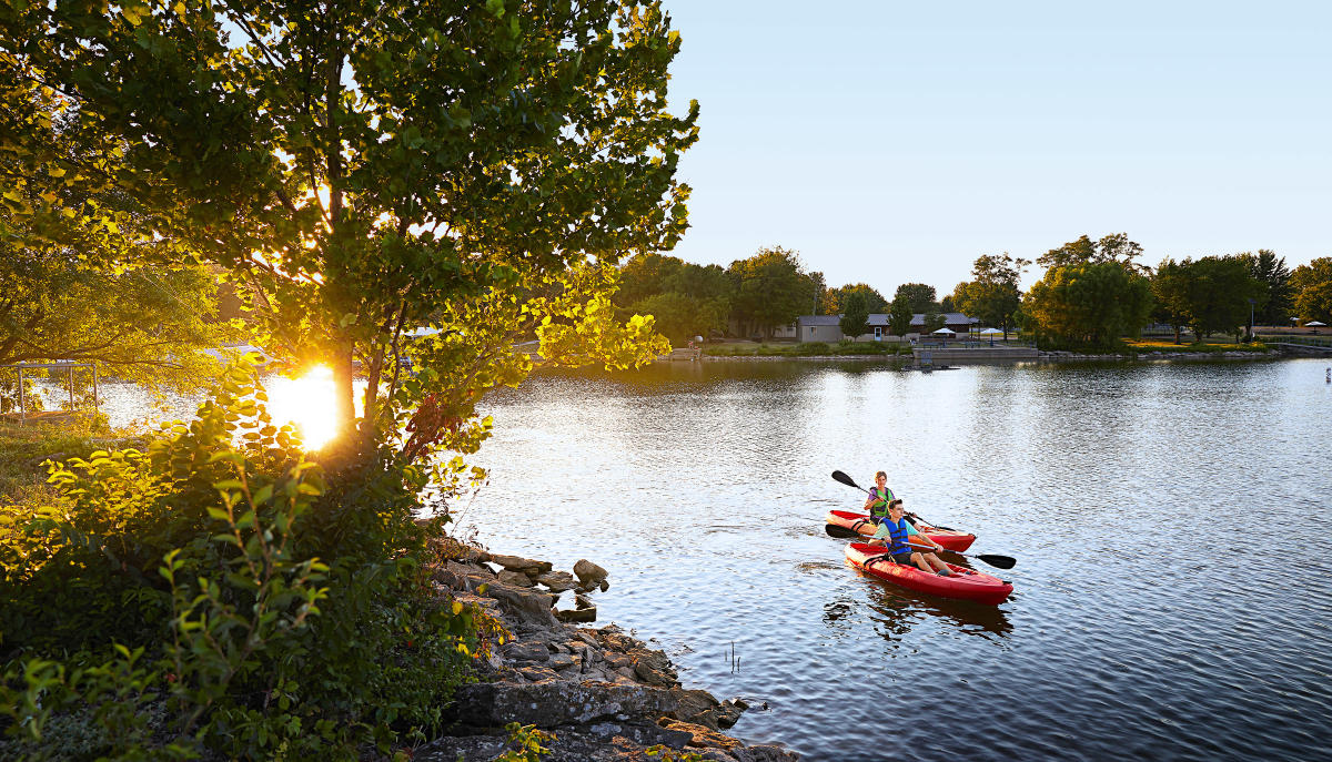 kayakers paddling on lake at sunset