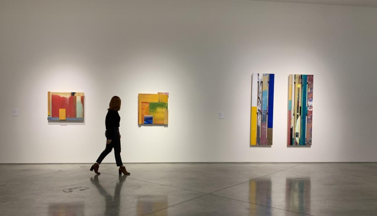 Woman walking in art museum looking at paintings