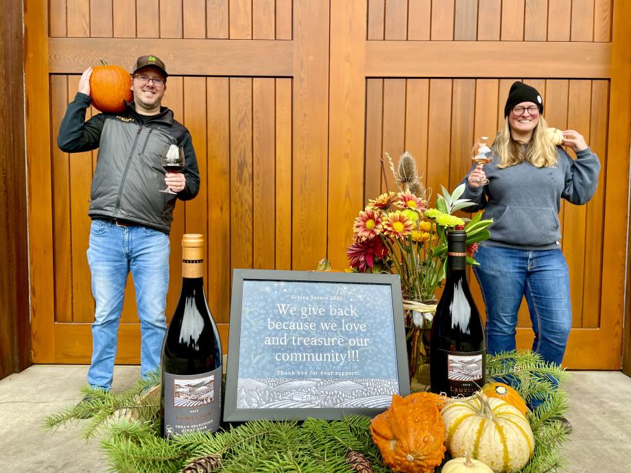 Lemelson winemakers hold Giving Season sign reading "we give back because we love and treasure our community"