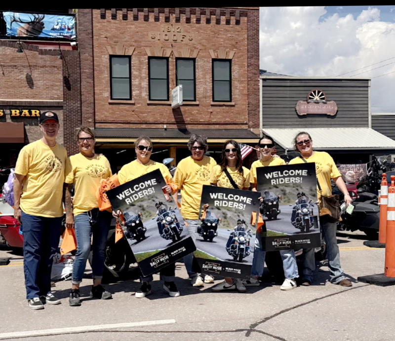 BH&B staff holding "Welcome Riders" signs at Rally Rush