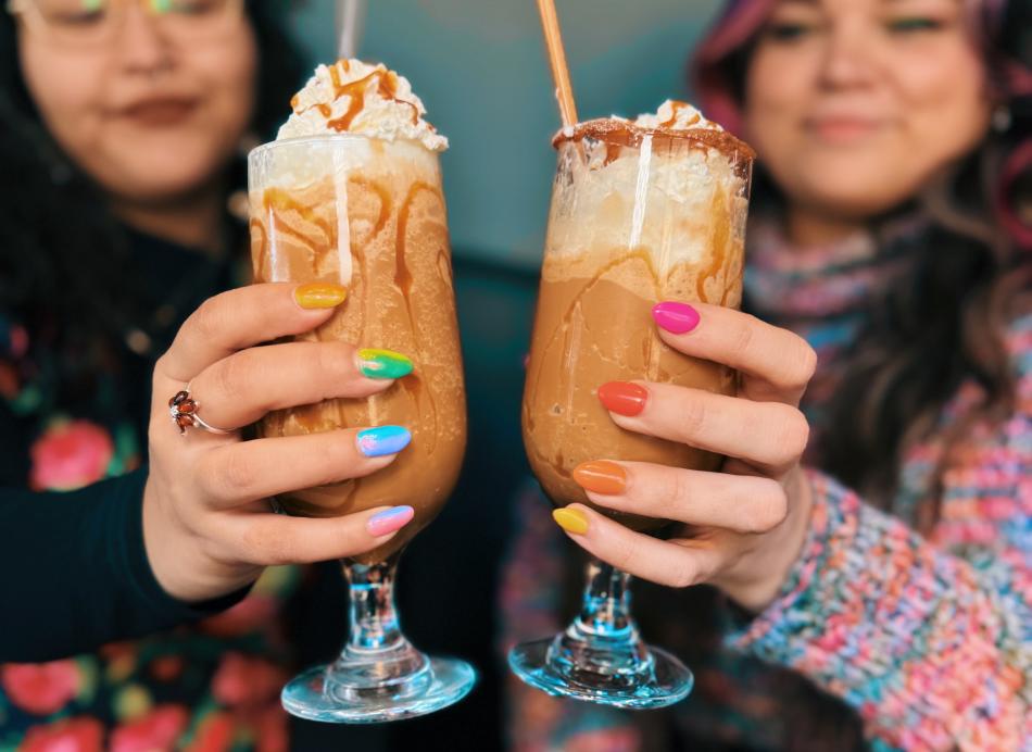 Two women holding espresso milkshakes at Domenico Dessert Bar
