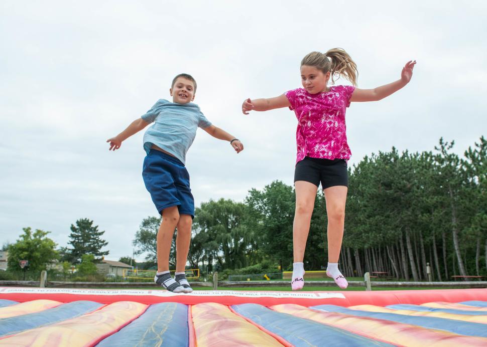 Two kids enjoy jumping on a trampoline at KOA Campground in Canandaigua / Farmington