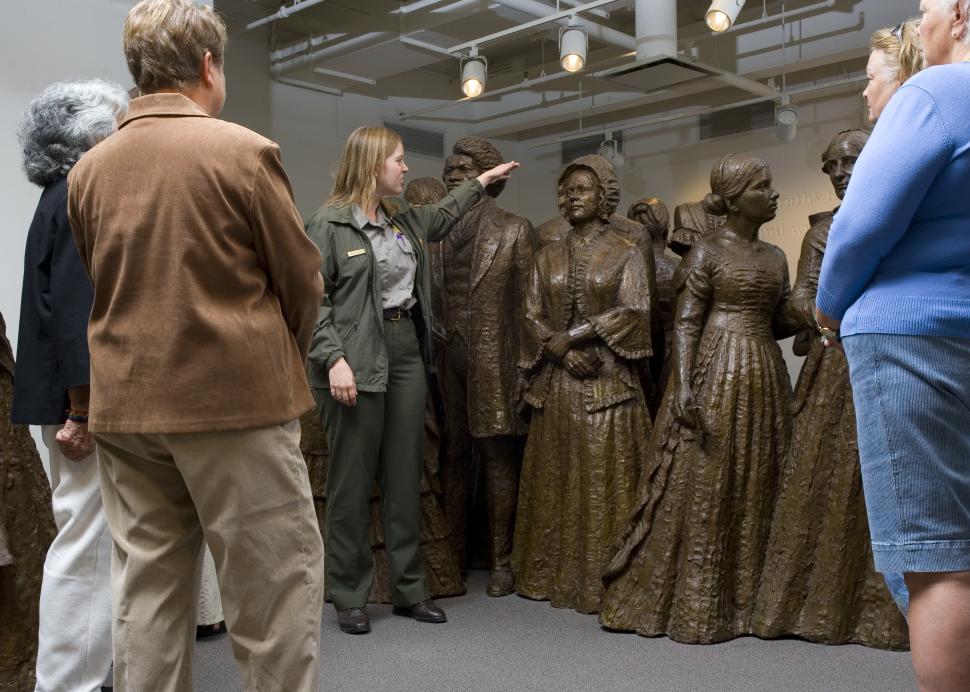 Guide, tour group, and statues of women at Women's Rights National Historical Park