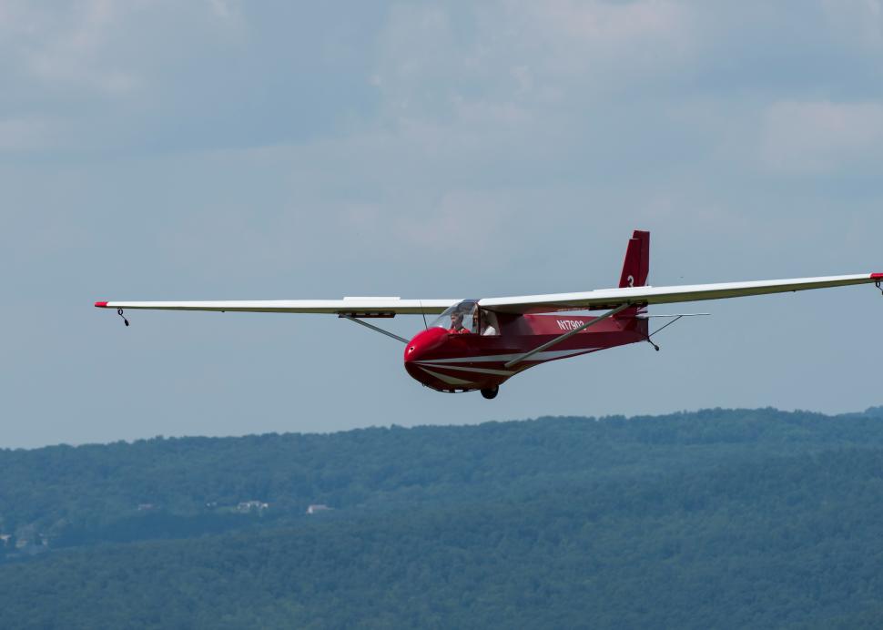 Plane soaring in front of mountains at National Soaring Museum