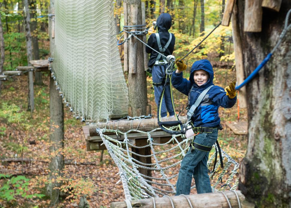 A customer posing on the obstacle course in the trees at Bristol Mountain Arial Adventures