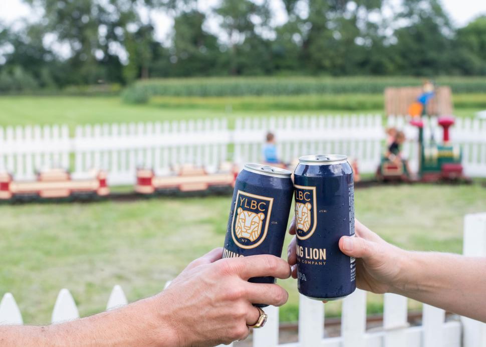 Two people cheer with young lion beer cans at the Pick n' Patch in Stanley