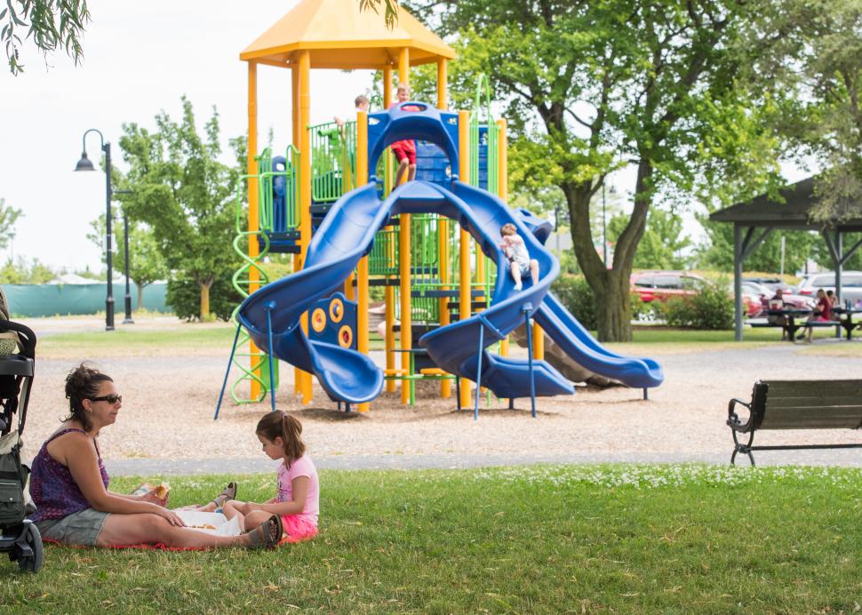 A mother and child sit in front of Kershaw Park's playground
