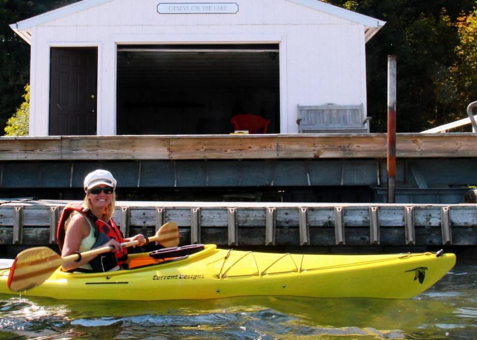 Woman kayaking in front of boathouse