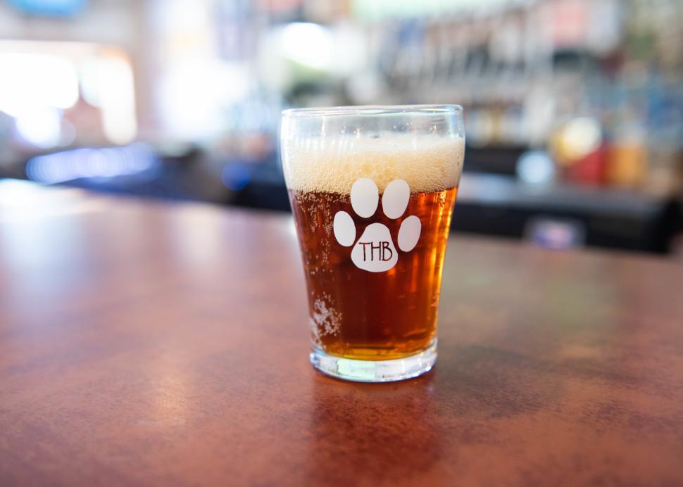 A glass of freshly brewed beer sits on a table inside of Three Huskies Brewing