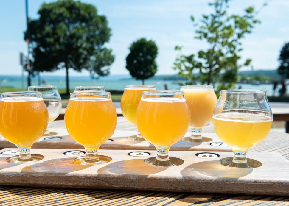 Glasses of beer sit in front of a lake vista at Young Lion Brewing Company in Canandaigua