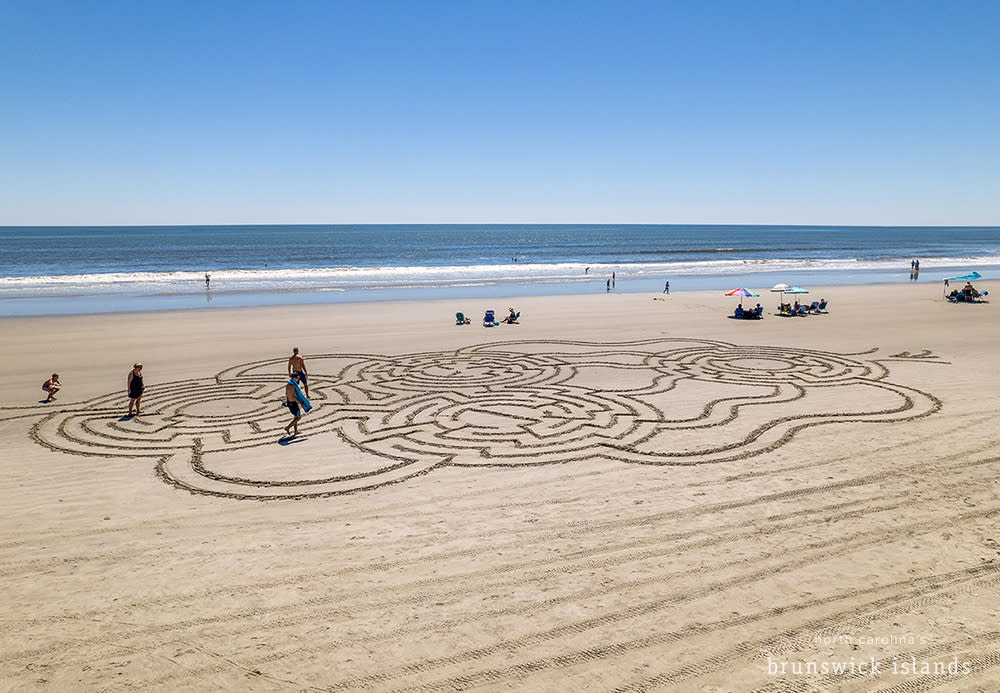 people navigating a maze drawn in the beach