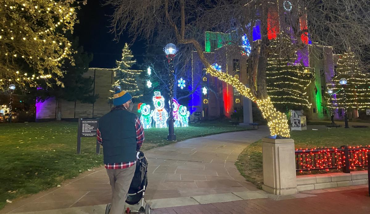 A person walking through the extravagant light displays at the Snow Much Fun event.