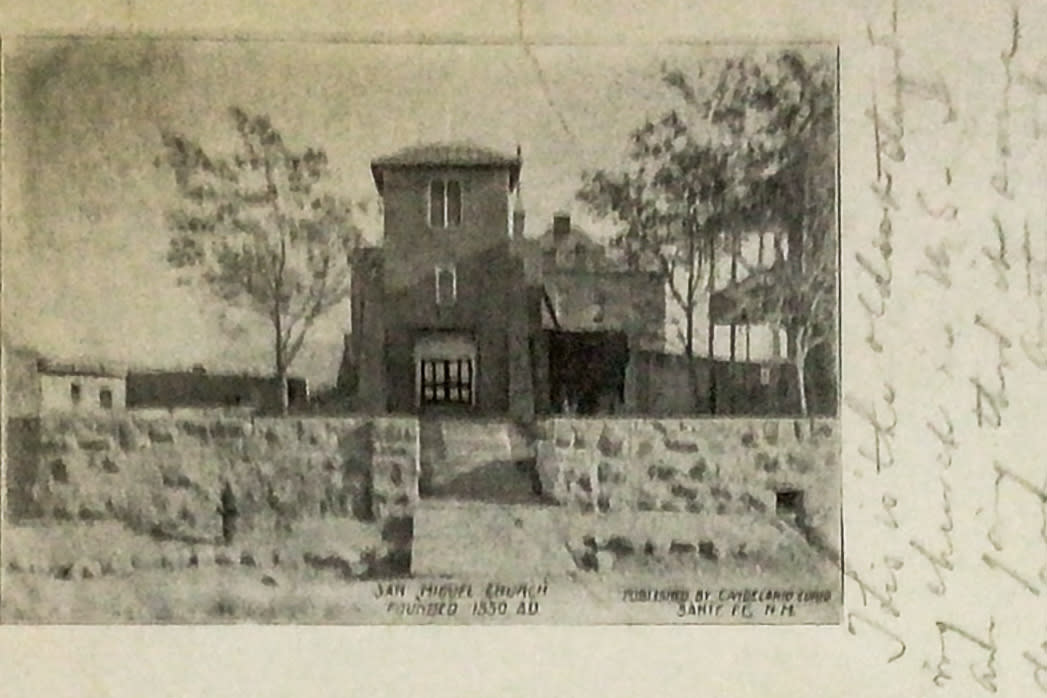 A vintage photograph shows a small stone-walled courtyard leading to a modest, tower-like church building labeled “San Miguel Church, Founded 1550 AD,” with trees visible behind the structure.