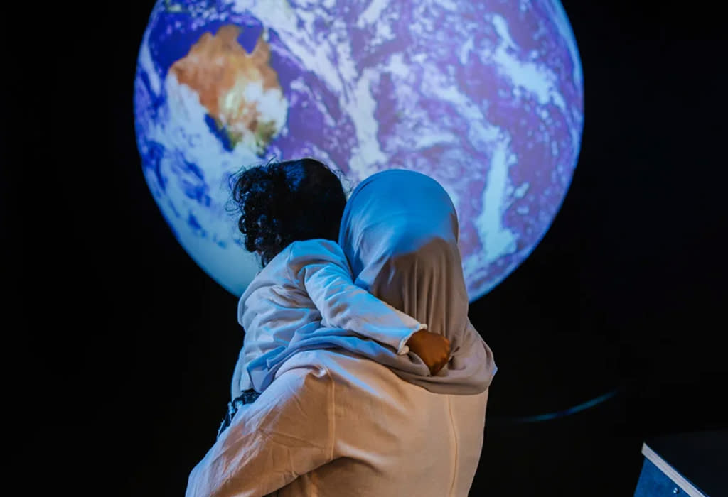 A woman holds her daughter up to look at the moon at the Kalamazoo Valley Museum.