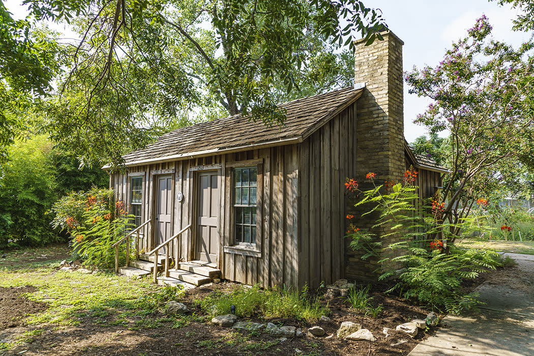 Historic Haskell House with blooming flowers around the exterior
