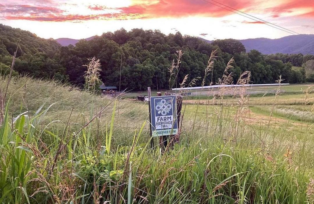 Picture of a sunset and a sign for the Farm Heritage Trail