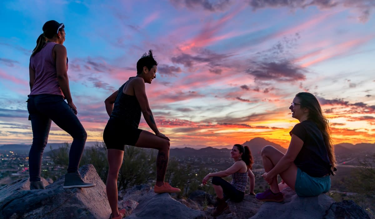 Friends watching a sunset on top of a Tucson mountain after a hike