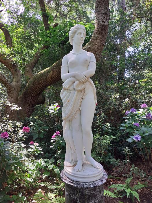 The statue of Virginia Dare surrounded by trees and flowers at the Elizabethan Gardens in Manteo, NC.