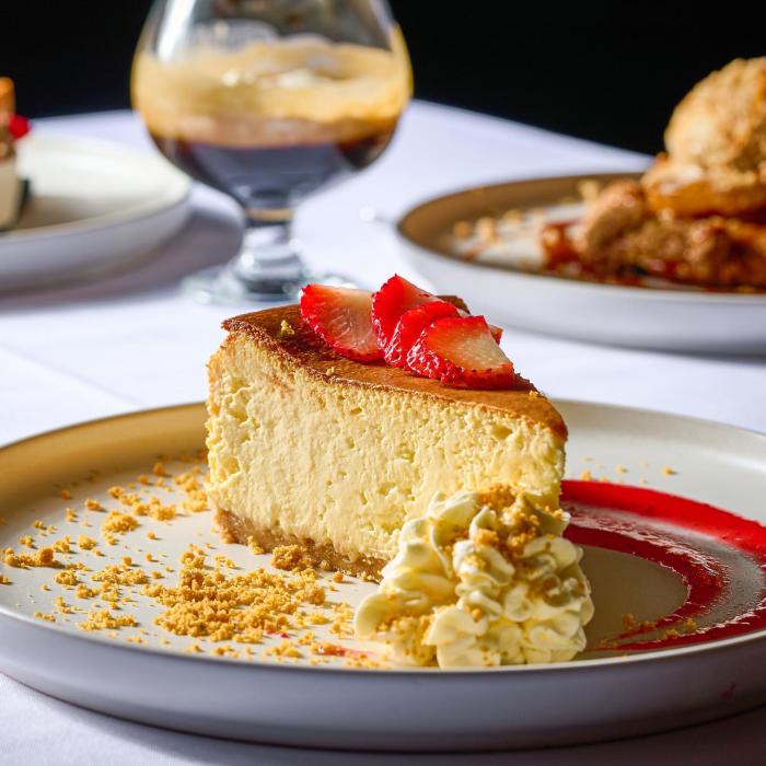 Slice of cheesecake with strawberries on top, sitting on a plate.