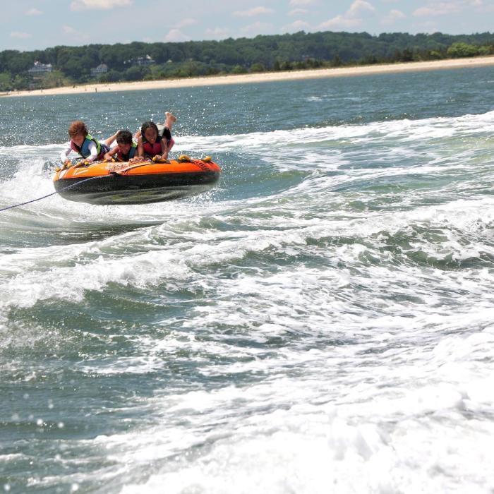 Kids on an inflatable being pulled behind a boat in the water
