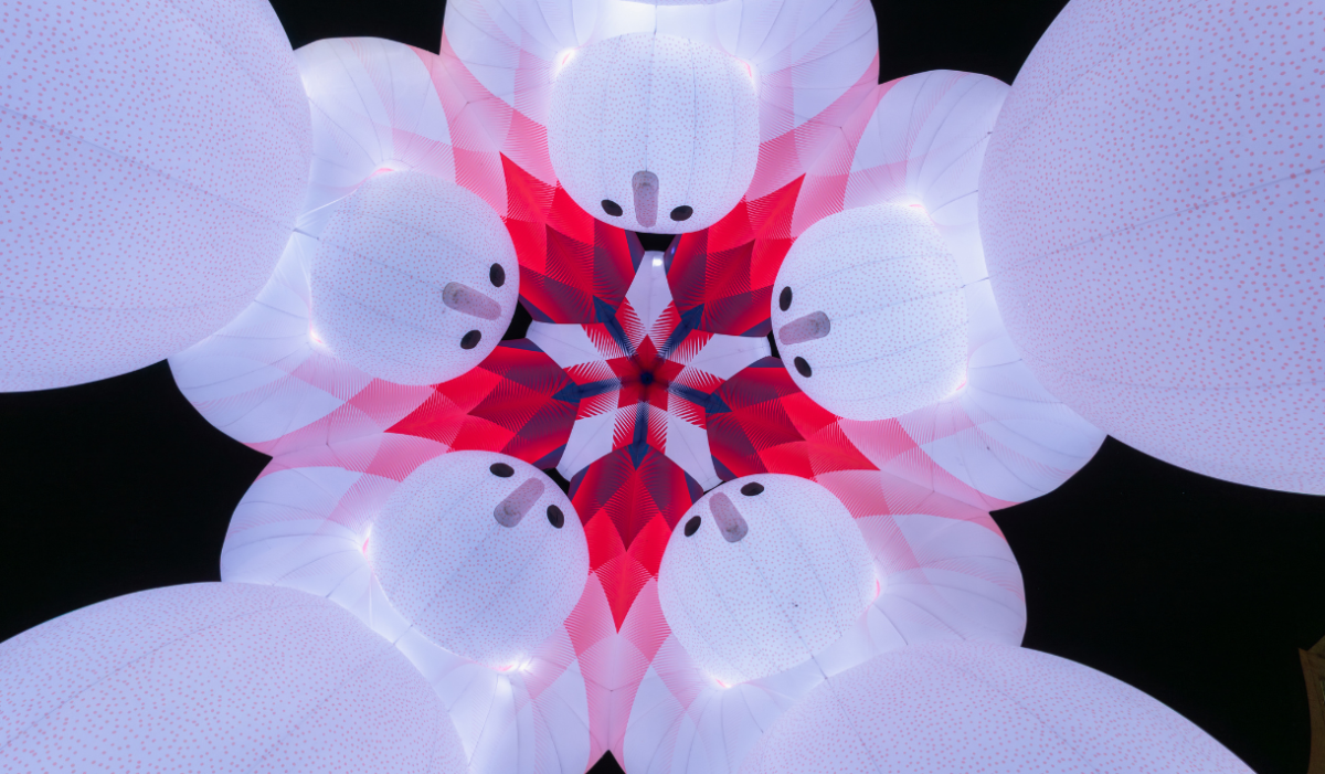 A photo of an art installation taken from the floor looking up. It is of five giant inflatable characters all leaning into each other.